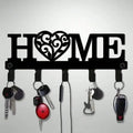 Black metal 'HOME' wall key rack with heart cutout and hooks, holding several sets of keys
