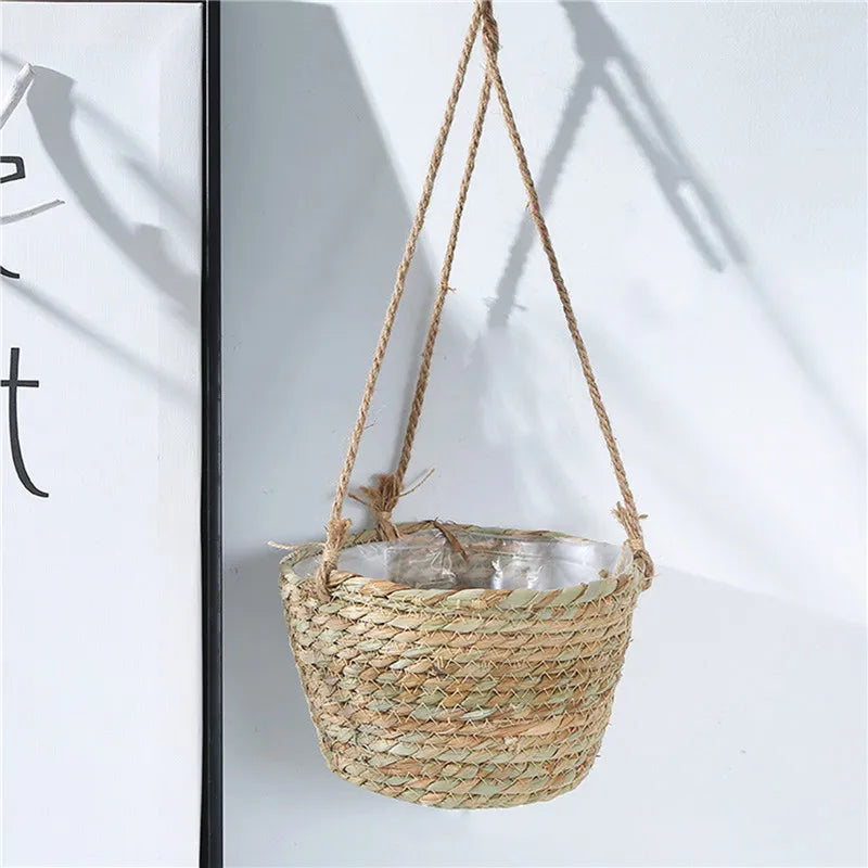 Single beige woven hanging planter basket with jute rope and plastic liner near a wall