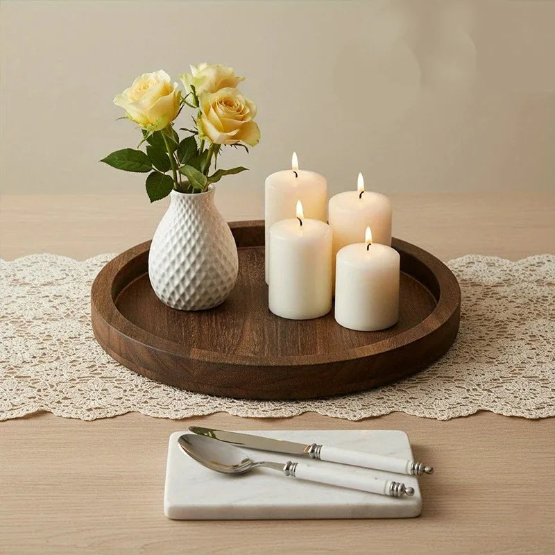 Wooden round tray on a lace runner, styled with a textured vase of yellow roses and four lit white candles
