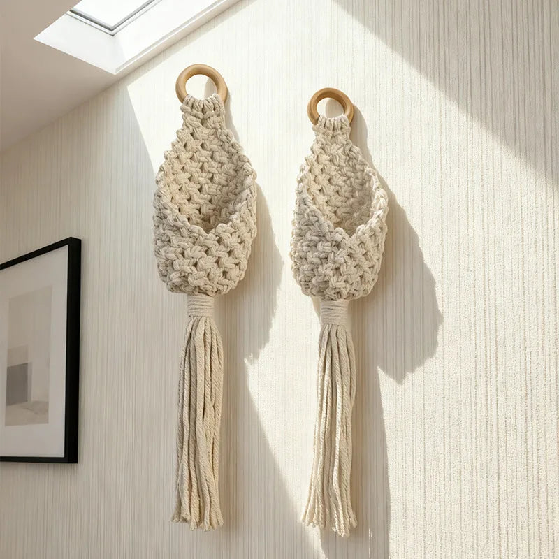 Pair of macramé cotton rope hanging wall baskets with tassels in bright hallway light