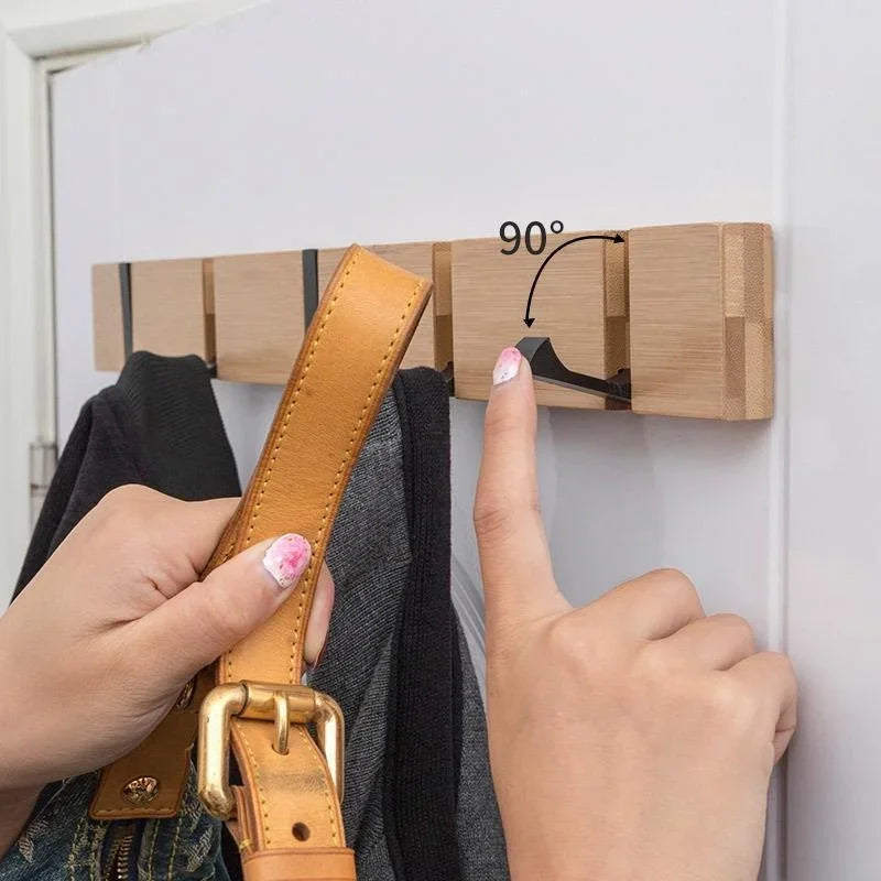 Person folding down a wooden wall hook with a 90-degree angle, ready to hang a leather bag