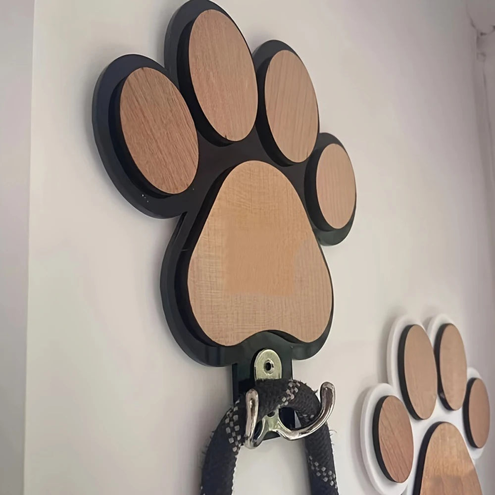 Side view of black paw print hook mounted on wall holding a leash