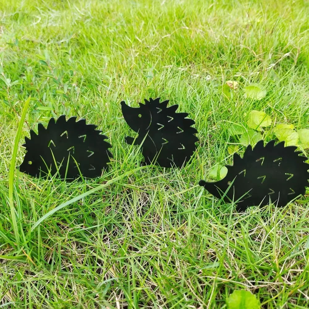 Three smaller hedgehog metal garden stakes grouped together outdoors