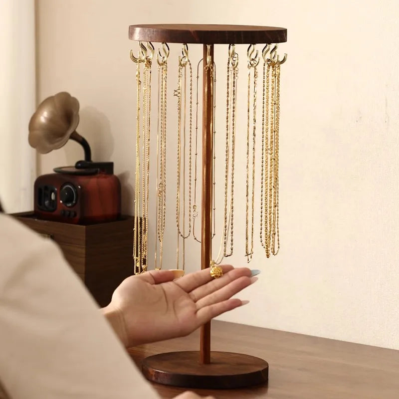 Person displaying ring next to necklace organizer stand on bedroom vanity