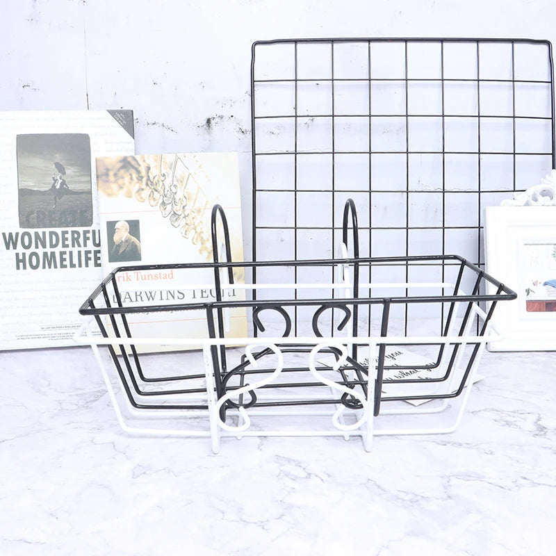 Two wire hanging baskets with hooks, in black and white, shown beside a wall grid on a marble surface