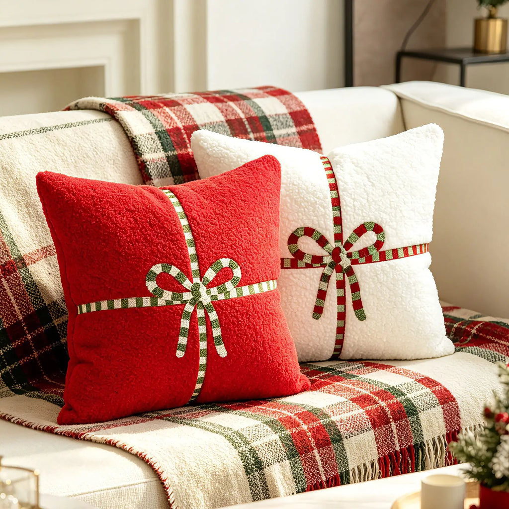 Red and beige teddy velvet pillow covers with festive bow design on a plaid sofa during Christmas