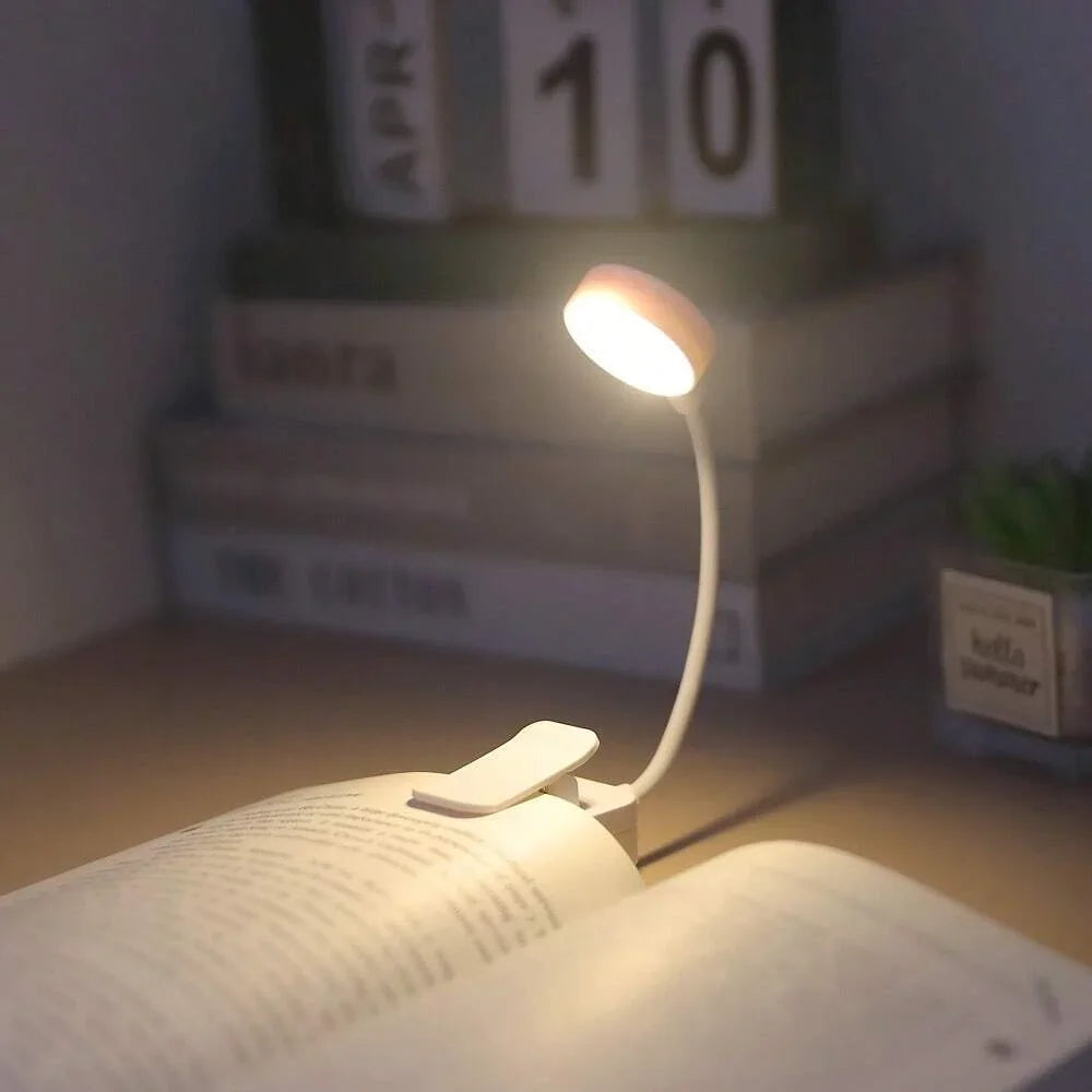 Clip-on LED reading light attached to an open book in a cozy room setting