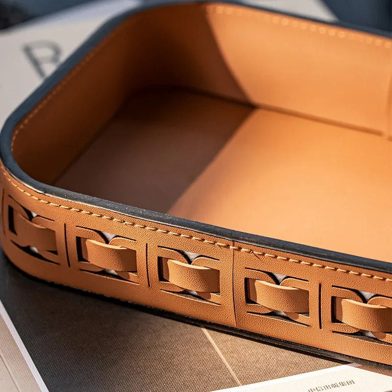 Detail of brown rectangular leather tray showing decorative cut-out stitched edges
