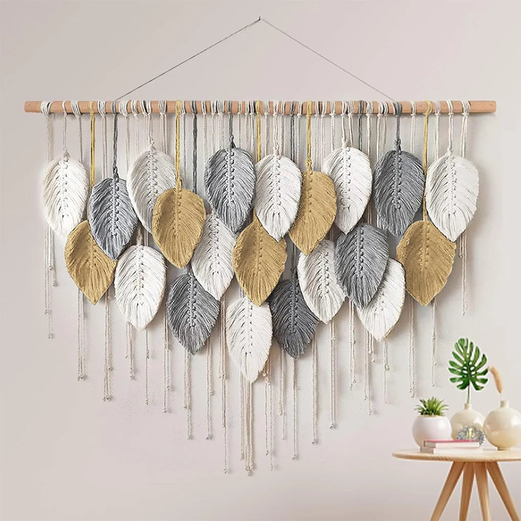 macrame wall hanging with golden, white, and gray leaves styled in a light interior