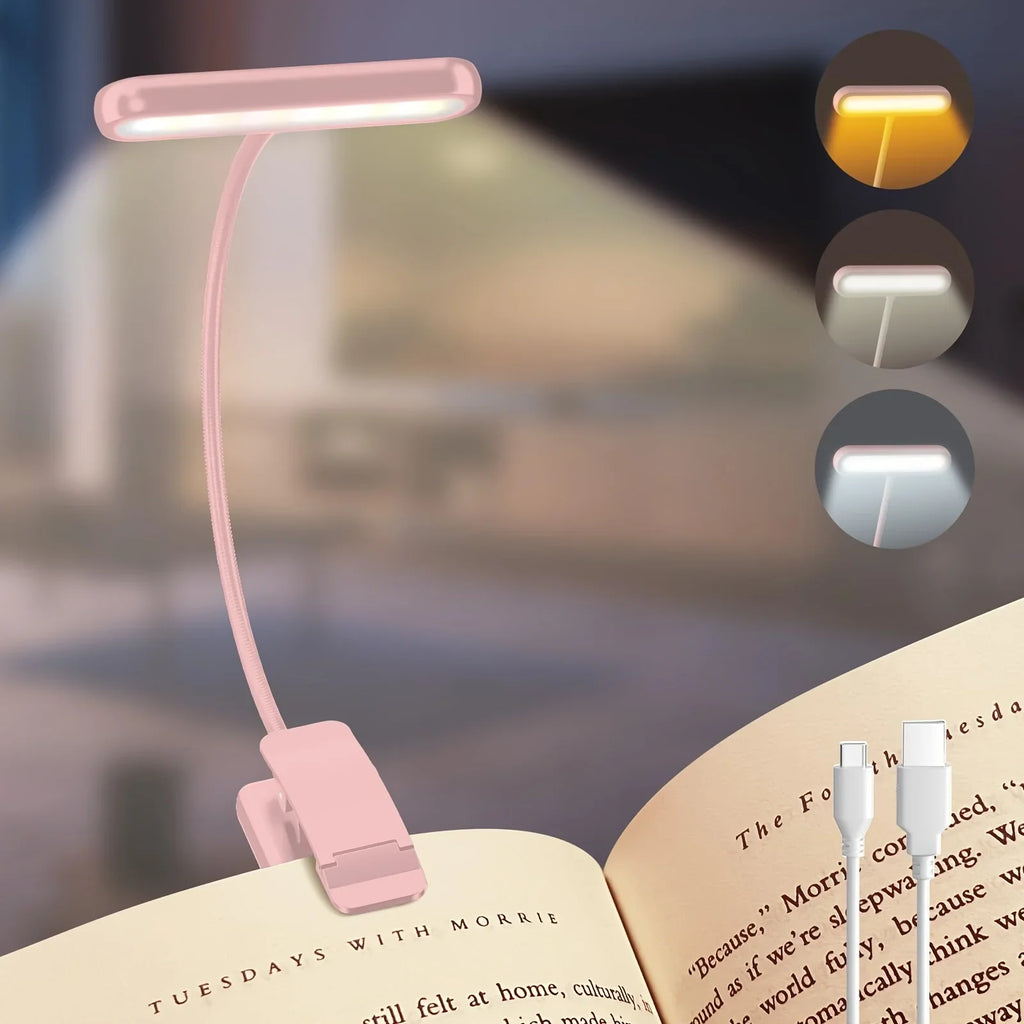 Pink clip-on reading lamp with adjustable neck, cable, and selectable color temperature, clipped to an open book.
