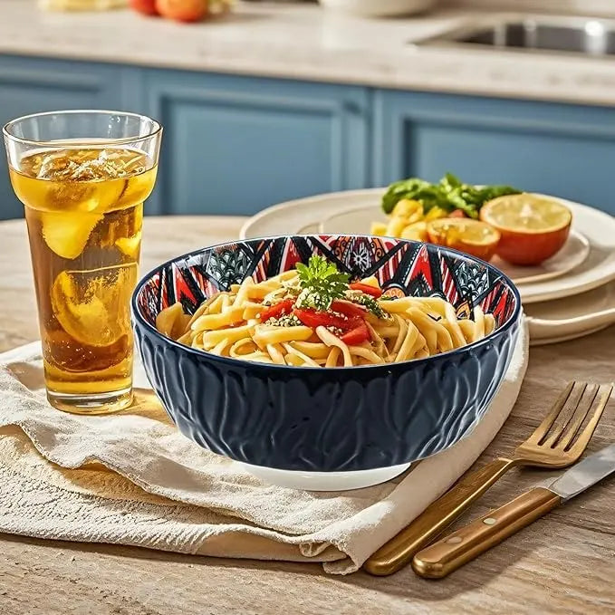 Blue floral porcelain bowl filled with pasta on a kitchen table, next to a glass of iced tea