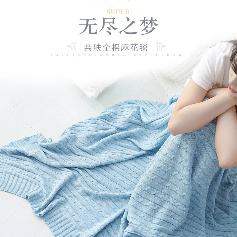Sky blue cable knit blanket covering person sitting on a bed