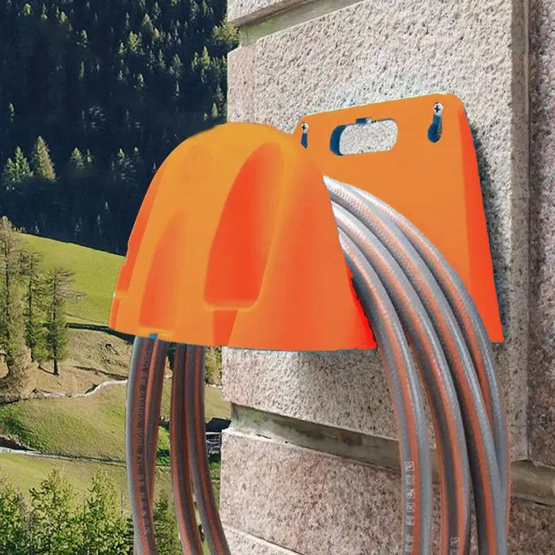 Orange wall-mounted garden hose holder installed on stone wall with coiled hose