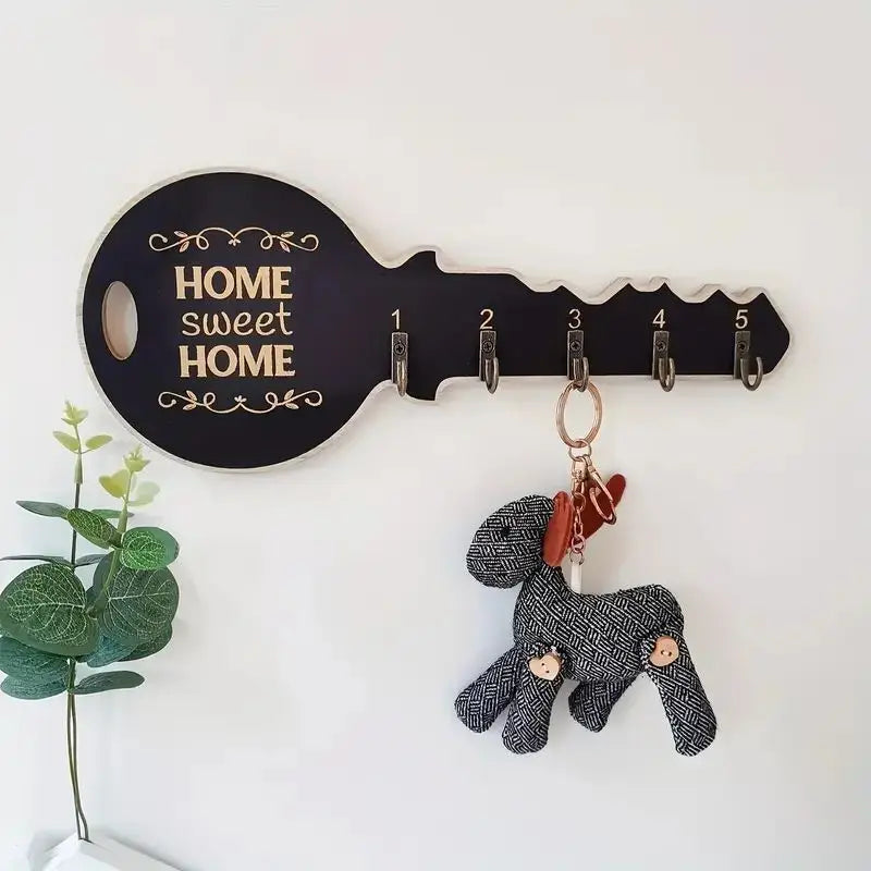 Black wood key-shaped wall key rack with 5 numbered hooks and 'Home Sweet Home' message installed in an entryway