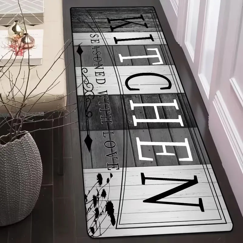 Rectangular kitchen runner rug with black and white 'Kitchen Seasoned With Love' script placed by a white door