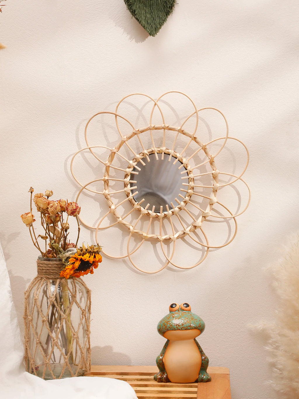 Handmade natural rattan wall mirror above a small wooden bench with decor