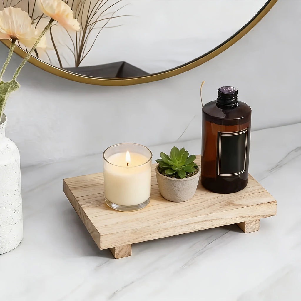 Light wood tray displaying a candle, small plant, and bottle by a mirror