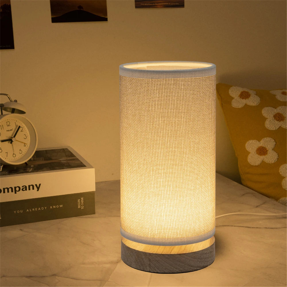 LED table lamp featuring a linen shade and wood base in a softly lit bedroom setup