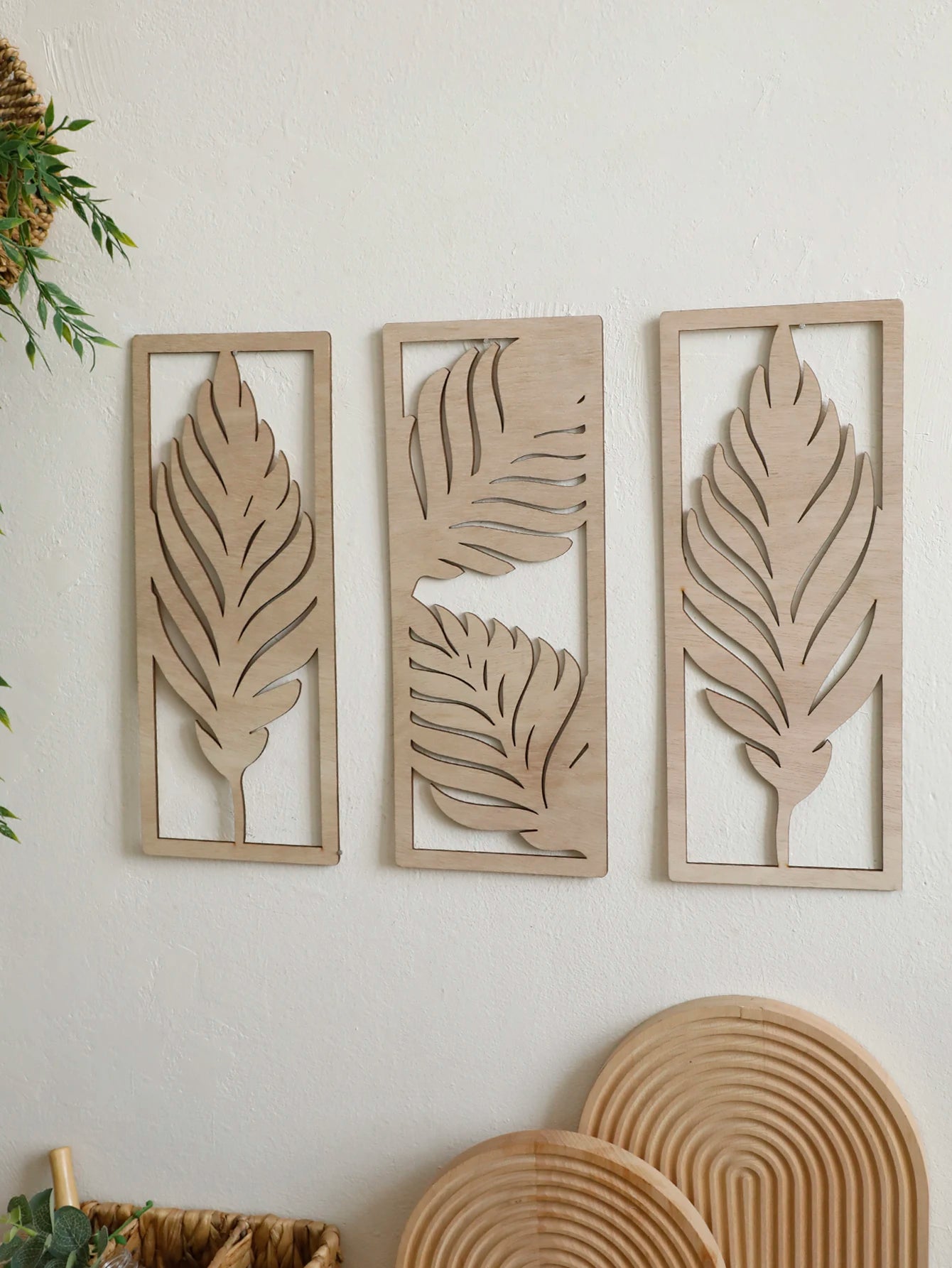 Set of three boho wooden leaf wall hangings on a white wall with natural accents