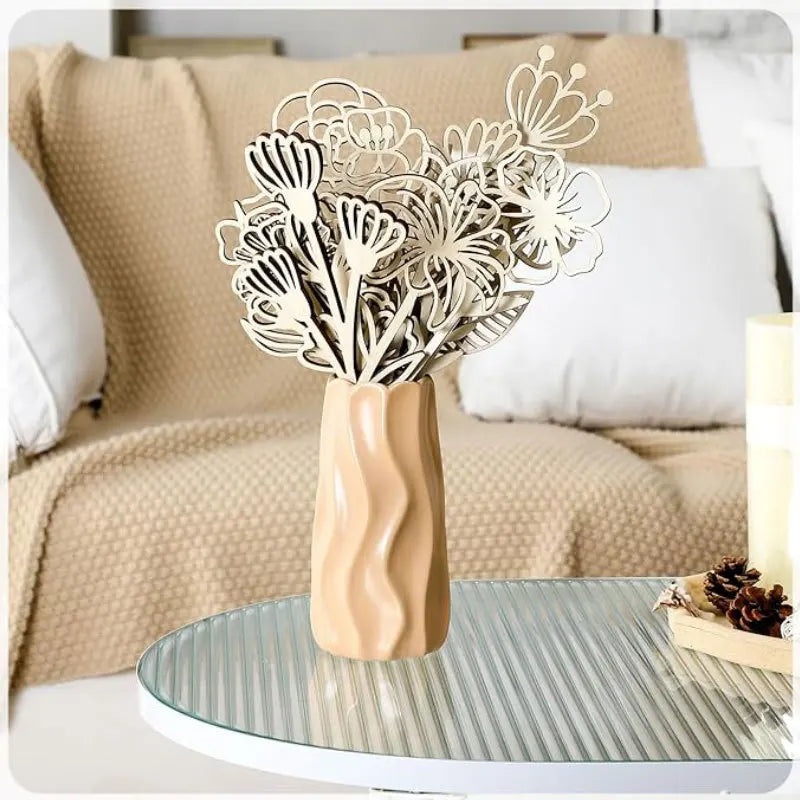 Unfinished wildflower wood cutouts in a sculpted tan vase on a glass coffee table in a cozy living room