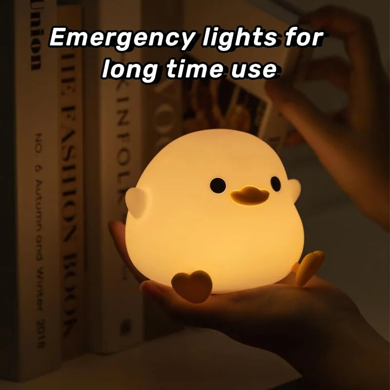 Person holding glowing silicone duck night light near bookshelf