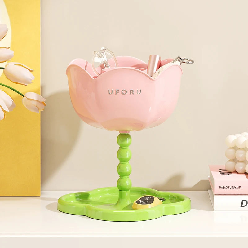 Pink flower-shaped organizer stand with green tray in use on a white surface, holding keys and accessories