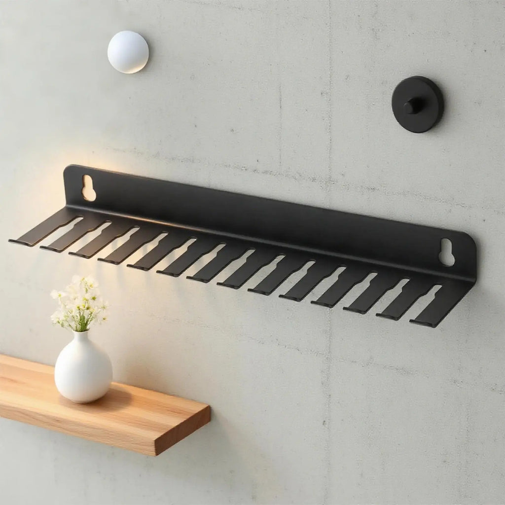 Black 13-slot steel wall cable organizer rack installed above a wooden shelf with a white vase