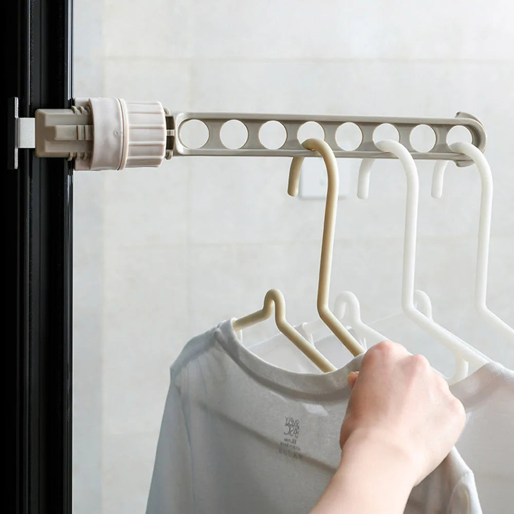 Gray wall-mounted clothes drying rack in use, holding multiple hangers with shirts in a bathroom setting.