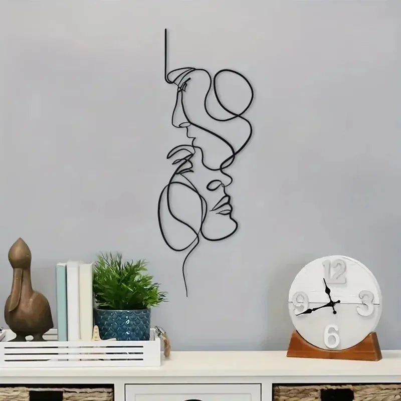 Minimalist black metal line art wall sculpture hung above a console with books, plant, and clock