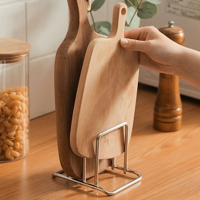 Hand placing cutting board into stainless steel rack on a wooden countertop