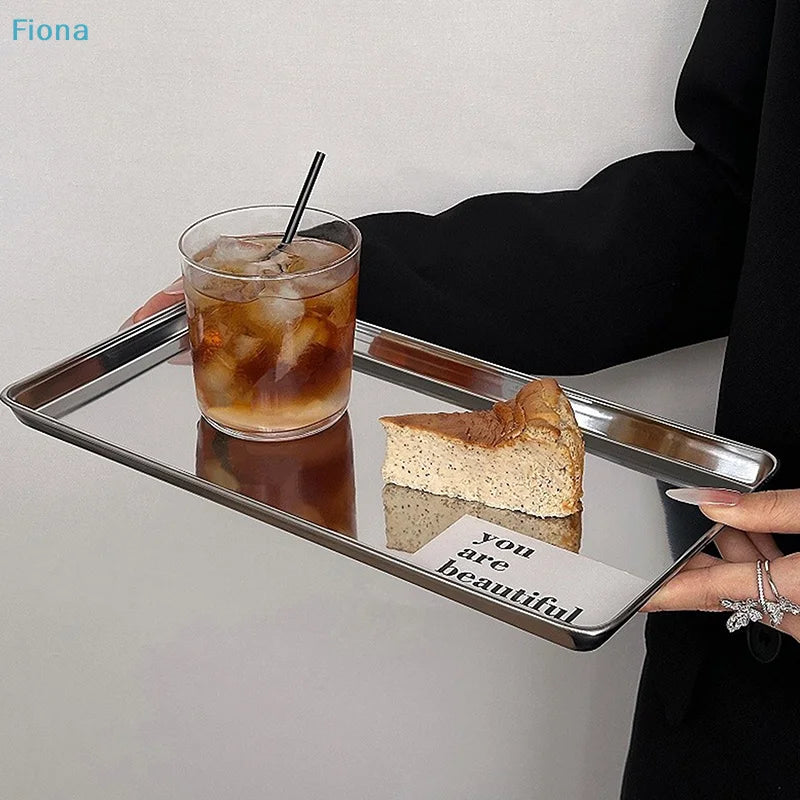 Minimalist stainless steel serving tray with iced coffee and cake slice on a light background