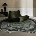 Modern living room with green lounge chair on green-accented stripe rug