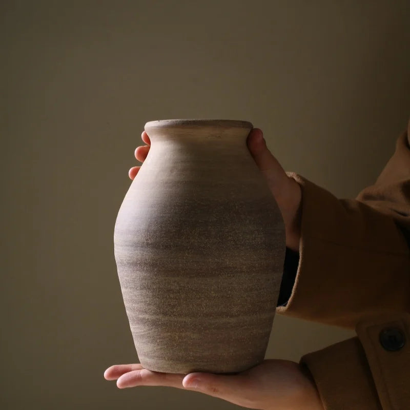 Close-up view of medium-sized rough clay vase held in two hands