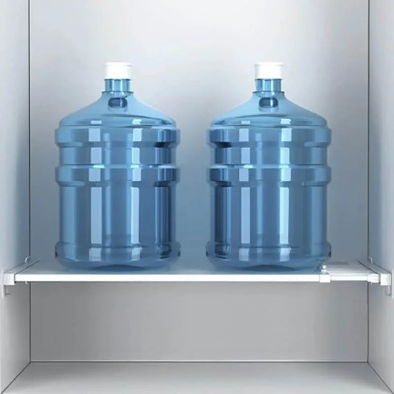 Two large water jugs on a shelf supported by clear acrylic brackets inside a white cabinet