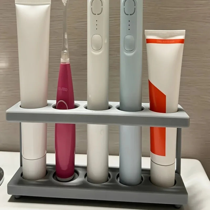 side angle showing electric toothbrushes and toothpaste stored in a gray two-level plastic toothbrush rack