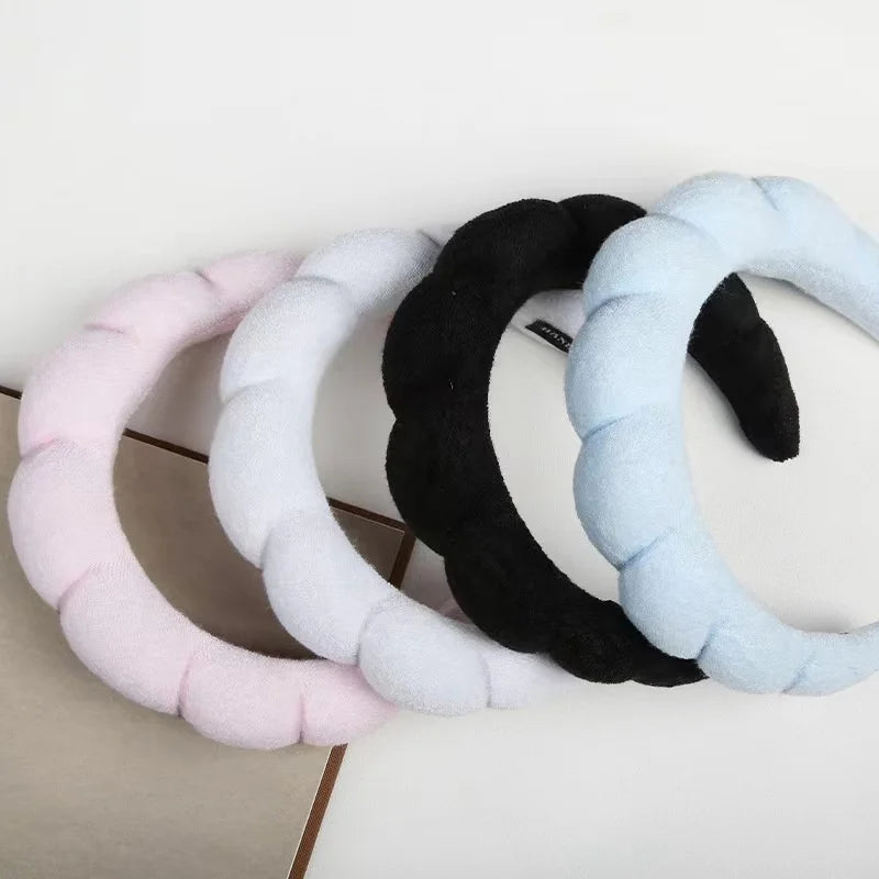 four padded headbands in pastel colors (pink, white, black, and light blue) arranged together