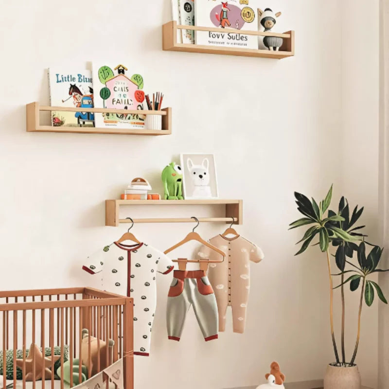 Three floating wood shelves mounted on a nursery wall, holding children's books, toys, and small decor items above a crib.