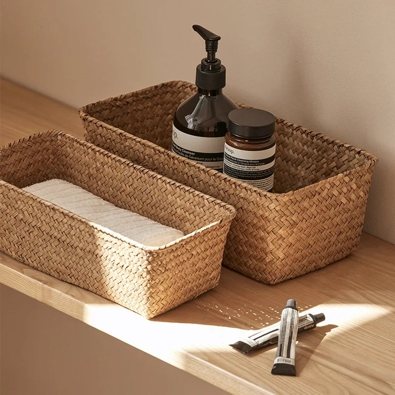 Two seagrass storage baskets on a vanity with bottles and a folded towel