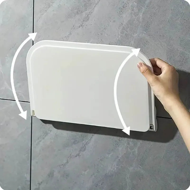 Hand folding down a white wall shelf mounted on a smooth tile wall