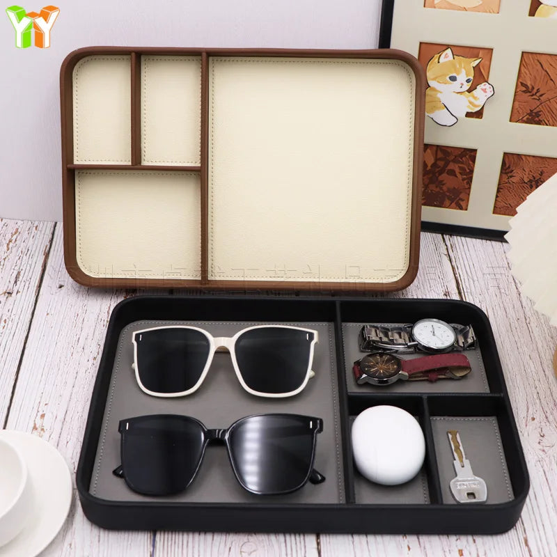 Two wood and black compartment trays holding sunglasses, watches, a key, and small electronics