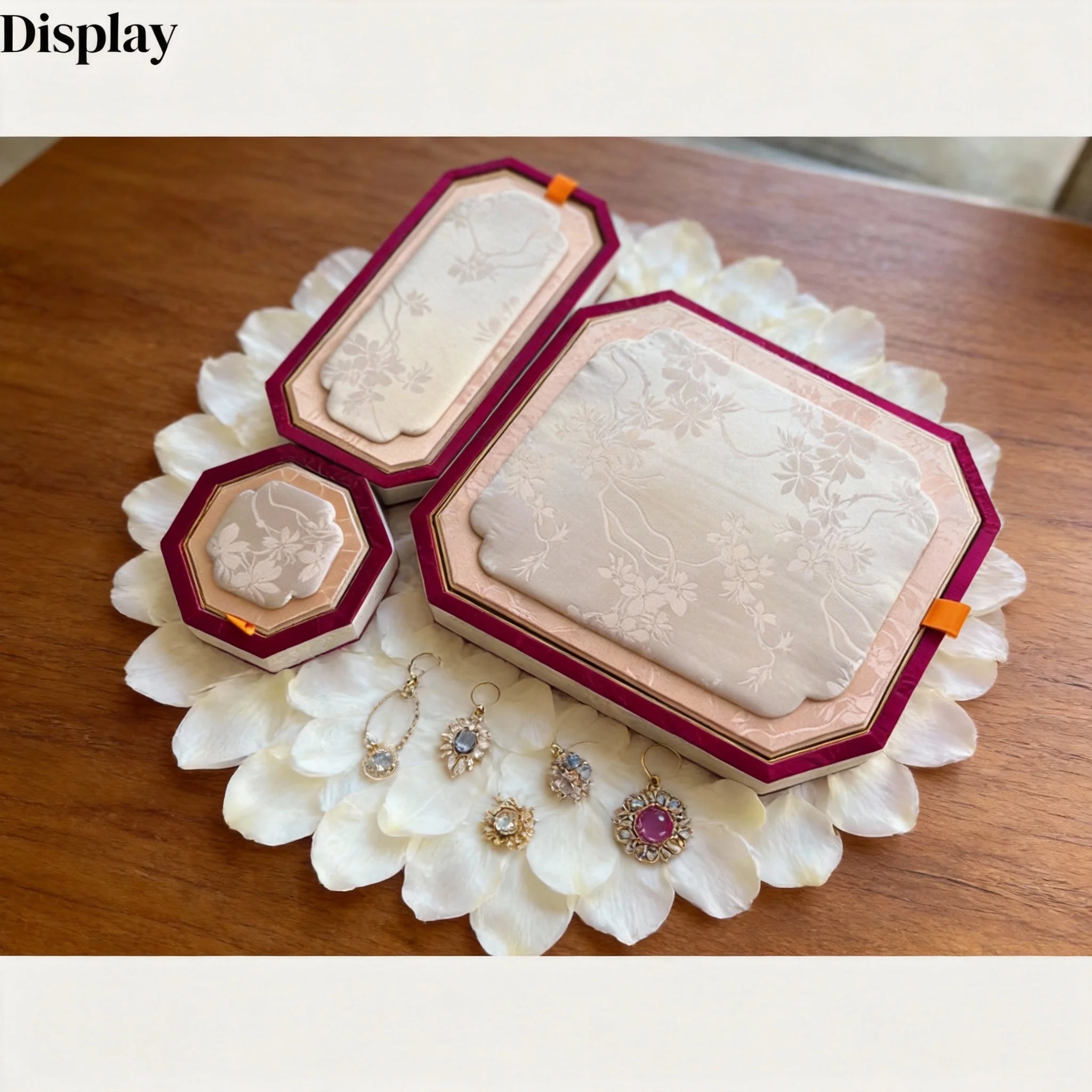 Set of floral jewelry trays on a bed of white petals, displaying earrings and decorative trays