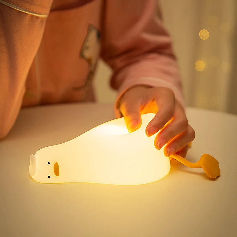 Hand gently squeezing soft glowing duck night light on a table