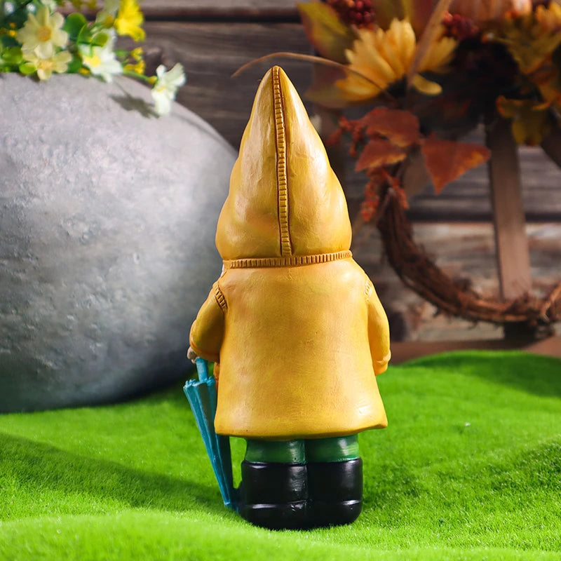 Back view of garden gnome statue in yellow raincoat holding umbrella, outdoors on grass