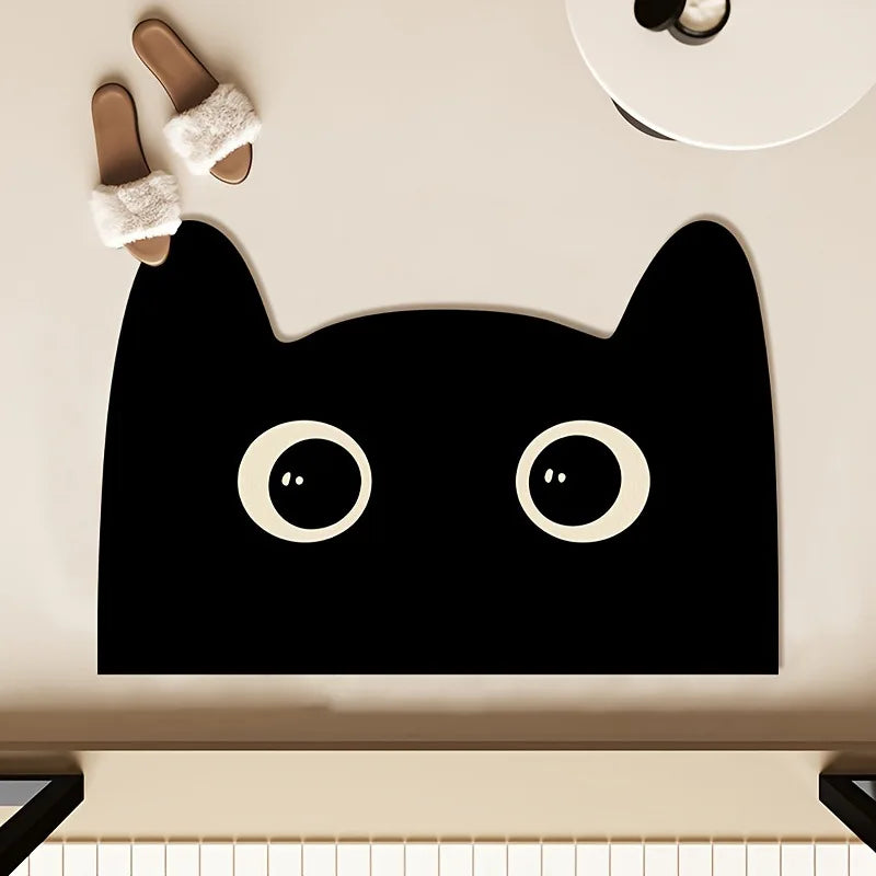Black cat bath mat with pointed ear design and large eyes, overhead view near slippers.