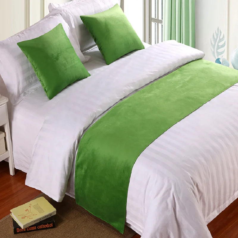 Green velvet bed runner and pillows on white bedding by window