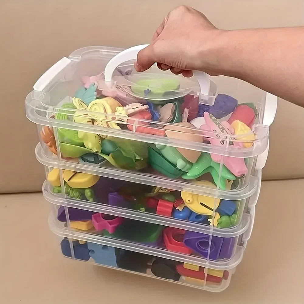 Hand lifting a clear three-tier storage box with white handle, filled with children's toys