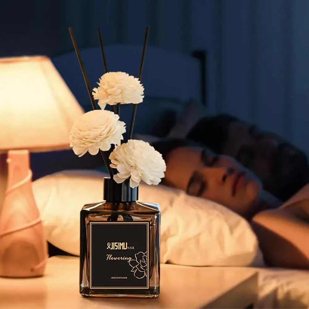 Jasmine reed diffuser on a bedside table with lamp and people resting in the background