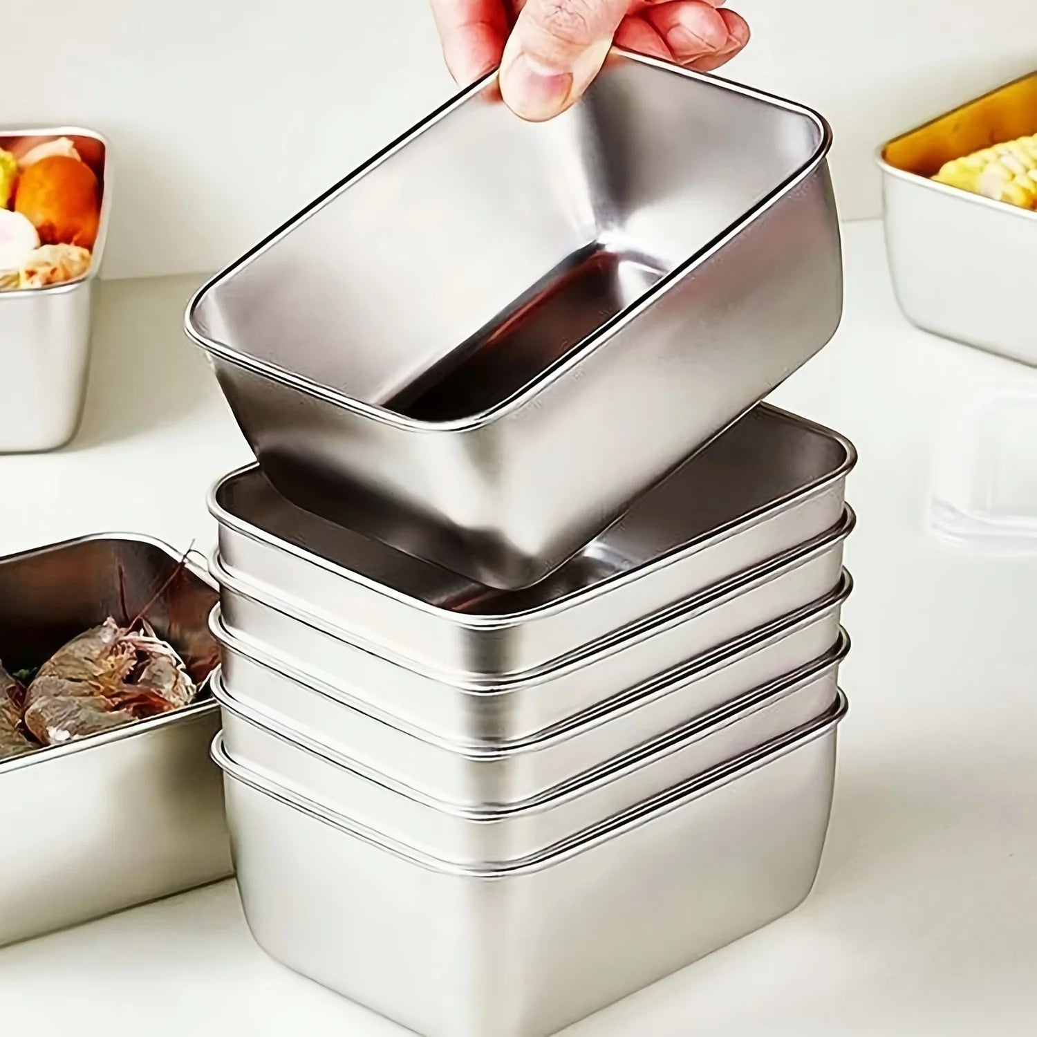 Hand stacking stainless steel food storage containers on kitchen counter