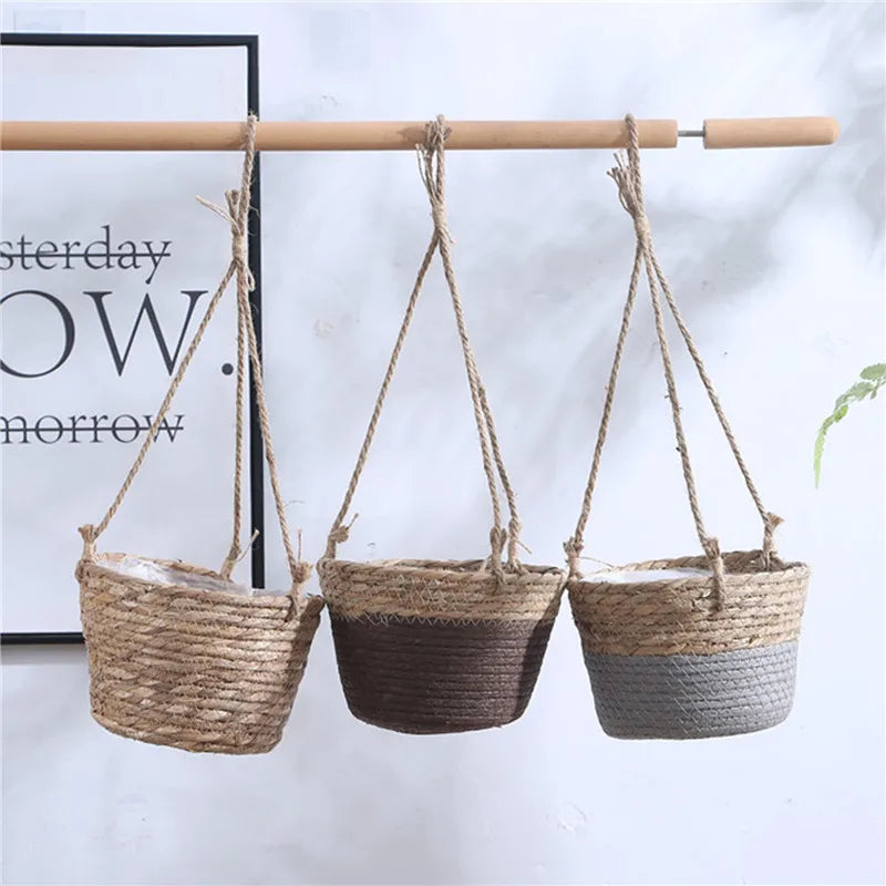 Three jute hanging planter baskets in beige, brown, and grey hanging from a wooden rod in a home setting