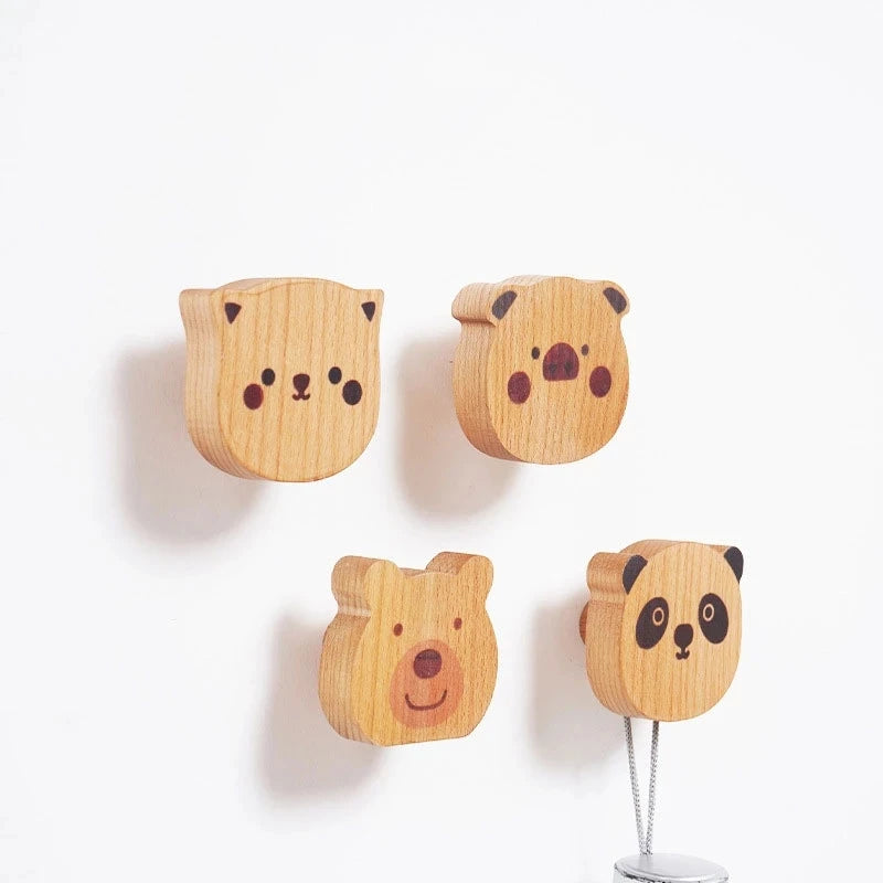 Close-up of four animal face wooden wall hooks mounted on the wall.